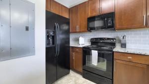 格林维尔Landing Modern Apartment with Amazing Amenities (ID1228X214)的厨房配有黑色家电和木制橱柜