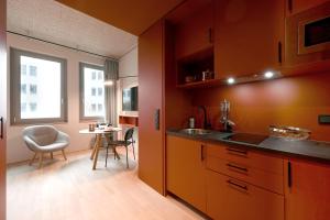 慕尼黑DEIN APART München的厨房配有橙色橱柜、桌子和窗户。