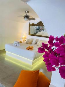 伊亚棕榈树小山别墅的一间卧室配有一张带镜子和鲜花的床