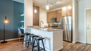 Brown DeerLanding Modern Apartment with Amazing Amenities (ID9985X43)的厨房配有带凳子的柜台和冰箱。
