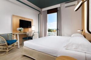 贾迪尼-纳克索斯UNAHOTELS Naxos Beach Sicilia的一间卧室配有一张床、一张书桌和一个窗户。