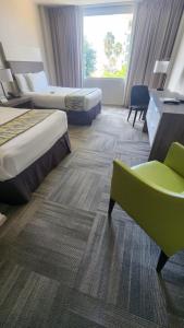 马亚圭斯马亚圭斯度假村和赌场度假酒店的酒店客房,设有两张床和一把绿色椅子