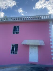 蒙特哥贝Three Palm Villa的粉红色的建筑,有白色的门和天空