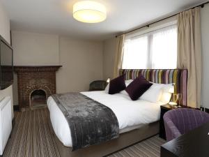 剑桥红狮酒店的一间卧室设有一张大床和一个壁炉