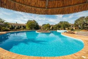 佩拉Country chic duplex in Algarve的一座铺有木地板并配有木制遮阳伞的大型游泳池