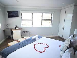 泰布尔维尤Atlantic Oasis Guest House的一间卧室配有一张大床,上面有红花