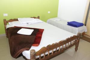 马迪凯里Madhuvana Guest House的一间卧室配有两张床、白色的床单和毛巾。