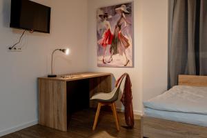 诺伊斯Jade&Jabo - Moderne möblierte Serviced Apartments - Düsseldorf-Neuss的一间卧室配有书桌、一张床和一把椅子