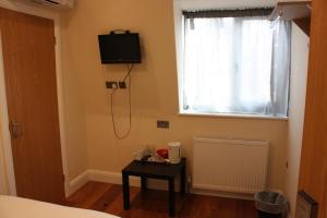伦敦奥林匹亚酒店的卧室配有壁挂式电视和桌子