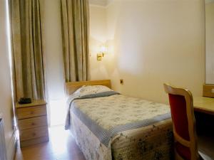 伦敦格雷舍姆酒店的一间小卧室,配有一张床和一张书桌