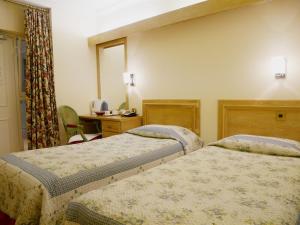 伦敦格雷舍姆酒店的酒店客房配有两张床和一张书桌