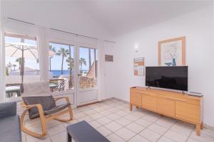 普拉亚布兰卡Playa Flamingo C的一间带电视和椅子的客厅