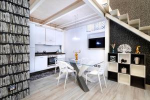 卡塔尼亚斯泰西科罗独家公寓式酒店的厨房以及带玻璃桌和白色橱柜的用餐室。