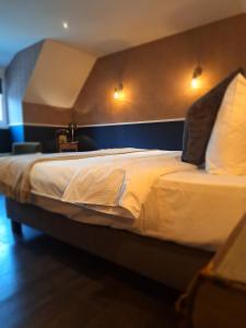 LasneChambres d'hôtes - Au Clos d'Amande的卧室配有一张带白色床单和枕头的大床。