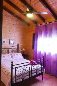 阿达莱斯3 bedrooms chalet with shared pool and wifi at Ardales的一间卧室配有一张床和一个带紫色窗帘的窗户