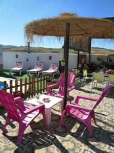 阿达莱斯3 bedrooms chalet with shared pool and wifi at Ardales的一组粉红色的椅子和桌子,放在伞下