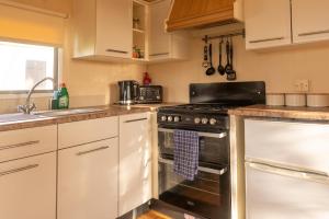 巴恩斯特珀尔No1 Meadow Brook的厨房配有白色橱柜和黑炉灶烤箱。