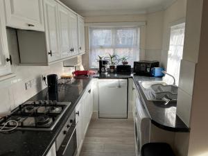 伦敦London Tottenham - good for centre and Redwood House-autism的厨房配有白色橱柜和黑色台面