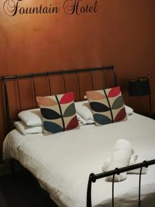 TuxfordThe Fountain Hotel的床上有枕头的床