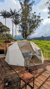 拉维加Glamping Reserva del Roble的一个带桌子的庭院内的帐篷和两把椅子