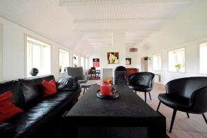 布拉万德Hygge Ho - mitten in der Natur mit Sauna und Spa的客厅配有黑色真皮沙发和椅子