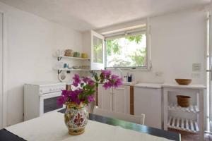 利卡塔Villa Caterina的厨房配有带紫色花卉的花瓶,摆放在桌子上