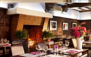 巴比松Les Pleiades Hôtel-Spa-Restaurant的一间带桌椅和壁炉的餐厅