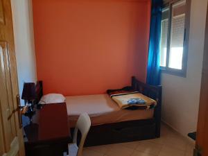 梅克内斯Charmant appartement à louer à meknès的一间小卧室,配有一张带橙色墙壁的床