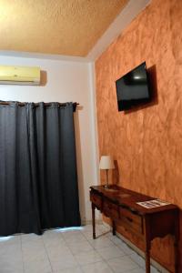 San LorenzoCasa Vieja Hotel y Restaurante的一间房间,配有一张桌子和一台墙上的电视