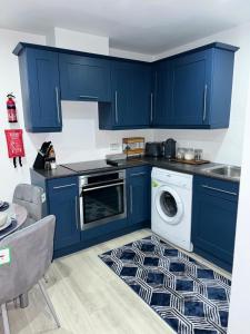 奥尔德肖特Blue Madison的厨房配有蓝色橱柜和洗衣机。