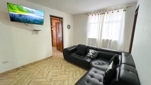 LíbanoAcogedor apartamento esquinero, a una cuadra del parque principal的客厅配有黑色沙发和平面电视。