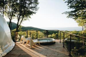 圣弗朗索瓦小河Dômes Charlevoix的一个带热水浴缸和两把椅子的甲板