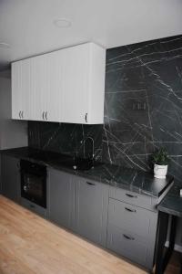 克雷廷加JAUKI STUDIJA KRETINGOS CENTRE的厨房配有黑色台面和白色橱柜