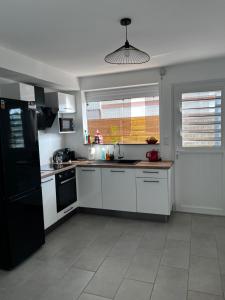 勒迪亚芒VILLA BOIS AND NATURE的厨房配有白色橱柜和黑色冰箱。