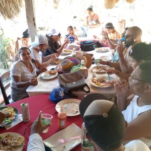 AltagraciaBeach cabin ometepe的一群坐在桌子旁吃食物的人