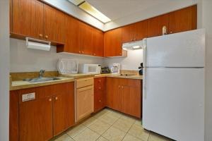 奥兰多I-DRIVE SUITES的厨房配有木制橱柜和白色冰箱。
