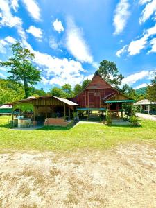 峇冬加里Kampung House (Minang) in Hulu Yam, Batang Kali的前面有草地的大型木质建筑