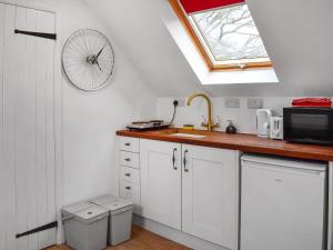 刘易斯Old Chimneys Studio的厨房配有白色橱柜,墙上挂有自行车