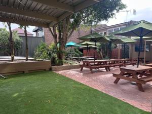 悉尼Tempe Hotel Sydney的一组野餐桌和雨伞