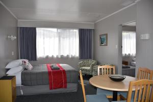Roxburgh罗克斯堡汽车旅馆的一间卧室配有一张床铺和一张桌子,还有一间用餐室