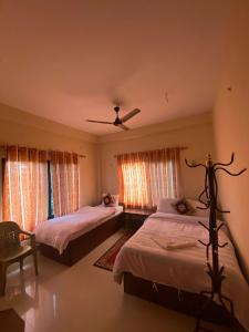 索拉哈Hotel BhupuSainik Sauraha的一间卧室配有两张床和吊扇