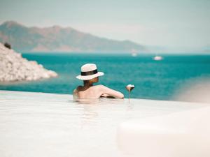 图兰克Perios Beach House - Adults Only的水中戴帽子的人,花