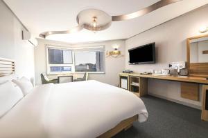 釜山Haute Hotel的酒店客房设有一张床、一张书桌和一台电视机。
