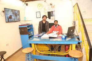 新德里Bunk Hostel Delhi Best Backpacking Accommodation的两个人坐在一张蓝色桌子上,手提电脑
