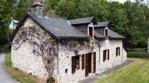 LignareixGîte de France à Lignareix 2 épis - Gîte de France 8 personnes 224的一座古老的石头建筑,里面种着鲜花