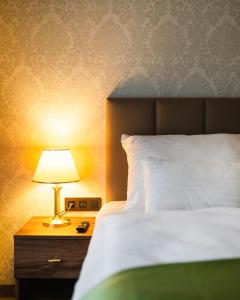 卡罗维发利Spa Hotel Villa Smetana的木床头柜上一张带灯的床