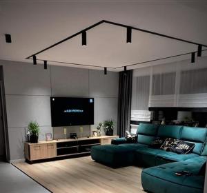 库多瓦-兹德鲁伊Apartament Roku 2024' - JELEŃ & NATURA的客厅配有蓝色的沙发和平面电视。