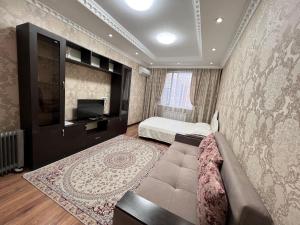 阿拉木图Apartmens in Complex Almaly 83-51的一间卧室配有一张床、一张沙发和一台电视。