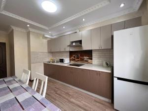 阿拉木图Apartmens in Complex Almaly 83-51的厨房配有桌子和白色冰箱。
