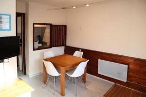 莱索尔Résidence Le Belvedere - Studio pour 5 Personnes 654的一间带木桌和白色椅子的用餐室